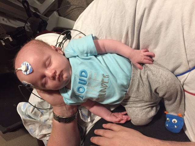 Baby in parent's arms with sensors on head
