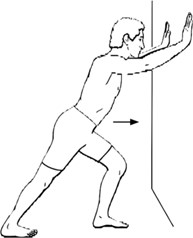 person with hands up against wall, leaning with one leg forward to stretch calf