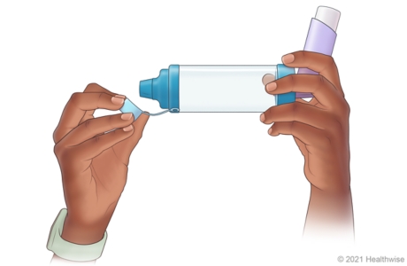 Person removing cap from end of inhaler opposite where inhaler was inserted.