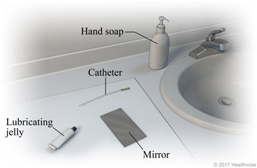 Bathroom sink area, showing supplies of hand soap, catheter, lubricating jelly, and mirror on clean cloth