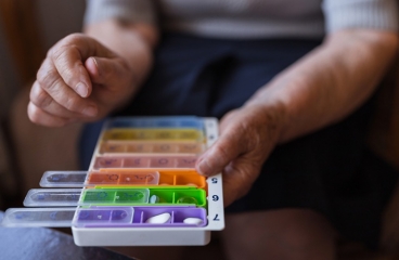 Person holding pillbox filled with medicines.