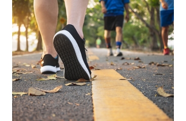 Person wearing sport shoes walking along outdoor path