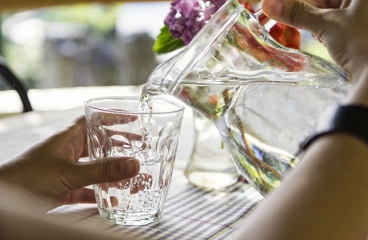 Person pouring glass of water from pitcher.