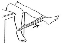 person sitting with elastic band around ankles, straightening one leg at a time