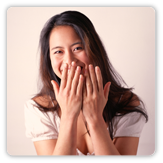 Photo of a young woman holding her hands up near her face