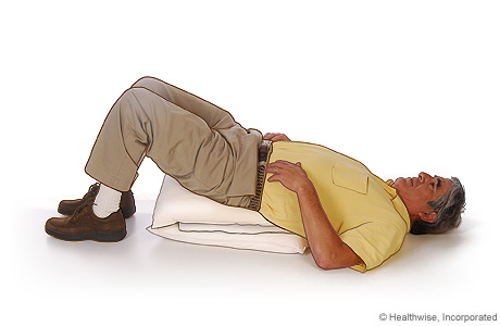 A man lying on his back to drain mucus from the front of his lungs.