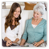 Photo of a young woman reading to older woman